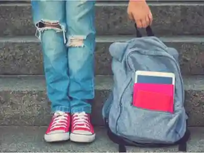 A student holding a backpack with school supplies in it.